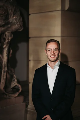 Jannik Trenz in a blazer in front of a stone wall