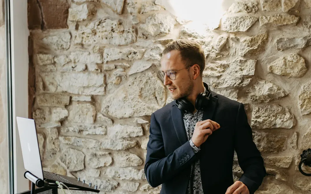 Jannik Trenz mit Kopfhörern am DJ-Pult vor einer Natursteinwand