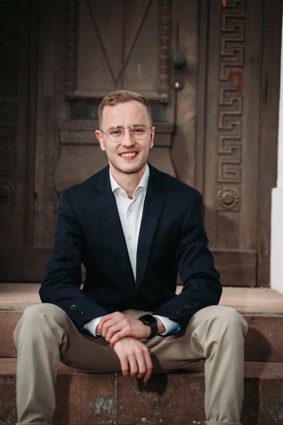 Jannik Trenz in a blazer in front of a wooden door